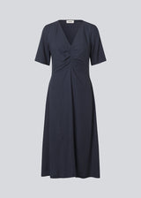 Long dress with short sleeves and a v-neck. MiguelMD SS dress has smock details and an invisible zipper on the side.