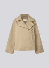 Beige jacket with an asymetrical closure. MillaMD jacket has two pockets in front, collar and wide sleeves.