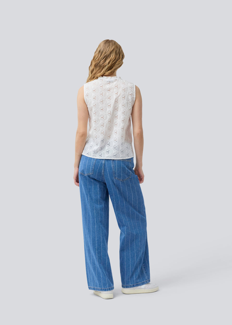 Sleeveless white top in broderie anglaise. NanetteMD top has a high neck and a button closure in front.
