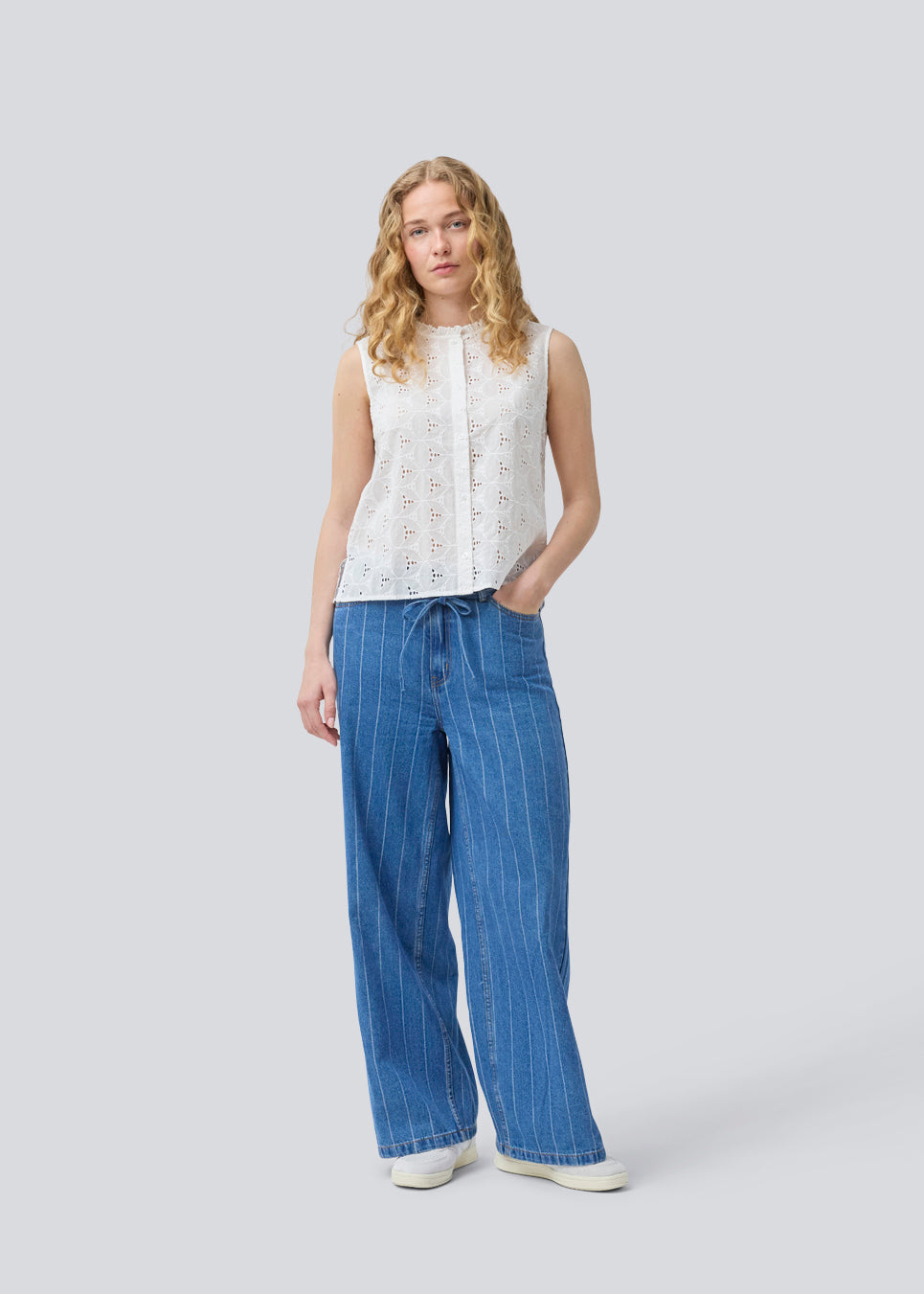 Sleeveless white top in broderie anglaise. NanetteMD top has a high neck and a button closure in front.