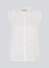 Sleeveless white top in broderie anglaise. NanetteMD top has a high neck and a button closure in front.