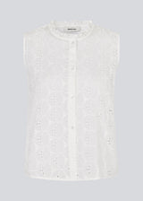 Sleeveless white top in broderie anglaise. NanetteMD top has a high neck and a button closure in front.