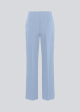 Classic pants in light blue with pressfolds and straight legs. Nelli pants are closed by an hidden zipper at the side with an elastic waistband for a more comfortable fit. The model is 175 cm and wears a size S/36