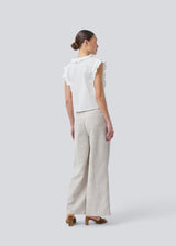 Sleeveless white top with frill details and a button closure in front. NIkkoMD top is slightly cropped and has a v-neck.