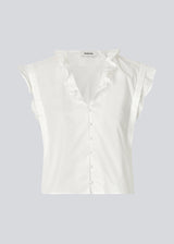 Sleeveless white top with frill details and a button closure in front. NIkkoMD top is slightly cropped and has a v-neck.