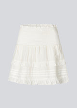 Short white skirt in 100% organic cotton. NillaMD short skirt has a loose skirt with pleats and frill details, and an elastic waist with a smock.