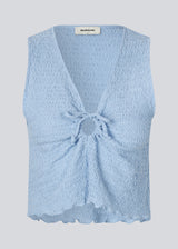 Sleeveless blue top with an opening with a tiedetail in front. NolineMD top is slightly cropped and has a loose fit and v-neck.