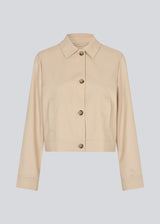 Short beige jacket with a shirt collar and wide sleeves. NormaMD jacket hasa button closure in front and two front pockets.