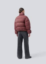 Red puffer jacket with a high neck in 100% recycled polyester. Odinmd jacket has a zipper closure and an adjustable strap at the sleeve. The model is 175 cm and wears a size s/36.