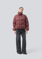 Red puffer jacket with a high neck in 100% recycled polyester. Odinmd jacket has a zipper closure and an adjustable strap at the sleeve. The model is 175 cm and wears a size s/36.