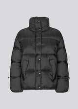 Black puffer jacket with a high neck in 100% recycled polyester. Odinmd jacket has a zipper closure and an adjustable strap at the sleeve. The model is 175 cm and wears a size s/36.