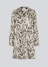 Printed shirt dress in 100% recycled polyester with collar, V-neck and button closure. The Saber-limbed Print Dress has a tie at the waist and a knee length for a flattering cut.