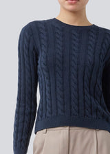 Fitted knit with a round neckline in 100% organic cotton. Sabremd o-neck has a cable pattern and an embroidered chest logo. The model is 175 cm and wears a size s/36.