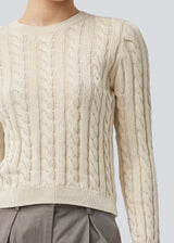 Fitted knit with a round neckline in 100% organic cotton. Sabremd o-neck has a cable pattern and an embroidered chest logo. The model is 175 cm and wears a size s/36.