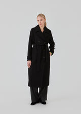 Classic, double-breasted wool coat in black with collar and notch lapels. ShayMD coat has a wide tiebelt at waist, shoulder straps, wide cuffs and open yoke. With lining and single back vent.