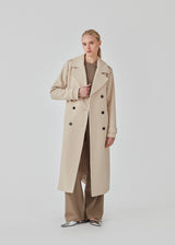 Classic, double-breasted wool coat in beige with collar and notch lapels. ShayMD coat has a wide tiebelt at waist, shoulder straps, wide cuffs and open yoke. With lining and single back vent.