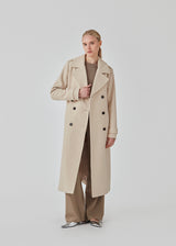 Classic, double-breasted wool coat in beige with collar and notch lapels. ShayMD coat has a wide tiebelt at waist, shoulder straps, wide cuffs and open yoke. With lining and single back vent.