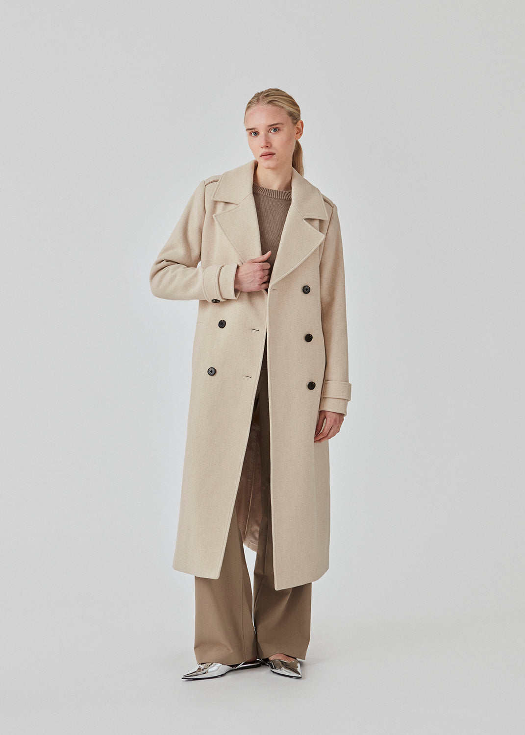 Classic, double-breasted wool coat in beige with collar and notch lapels. ShayMD coat has a wide tiebelt at waist, shoulder straps, wide cuffs and open yoke. With lining and single back vent.