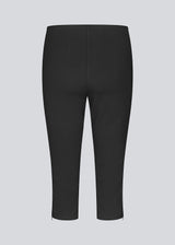 Black capri pants in a soft jersey material. Tanny capri pants has an elastic waistband and a slit with a zipper. The model is 175 cm and wears a size S/36.
