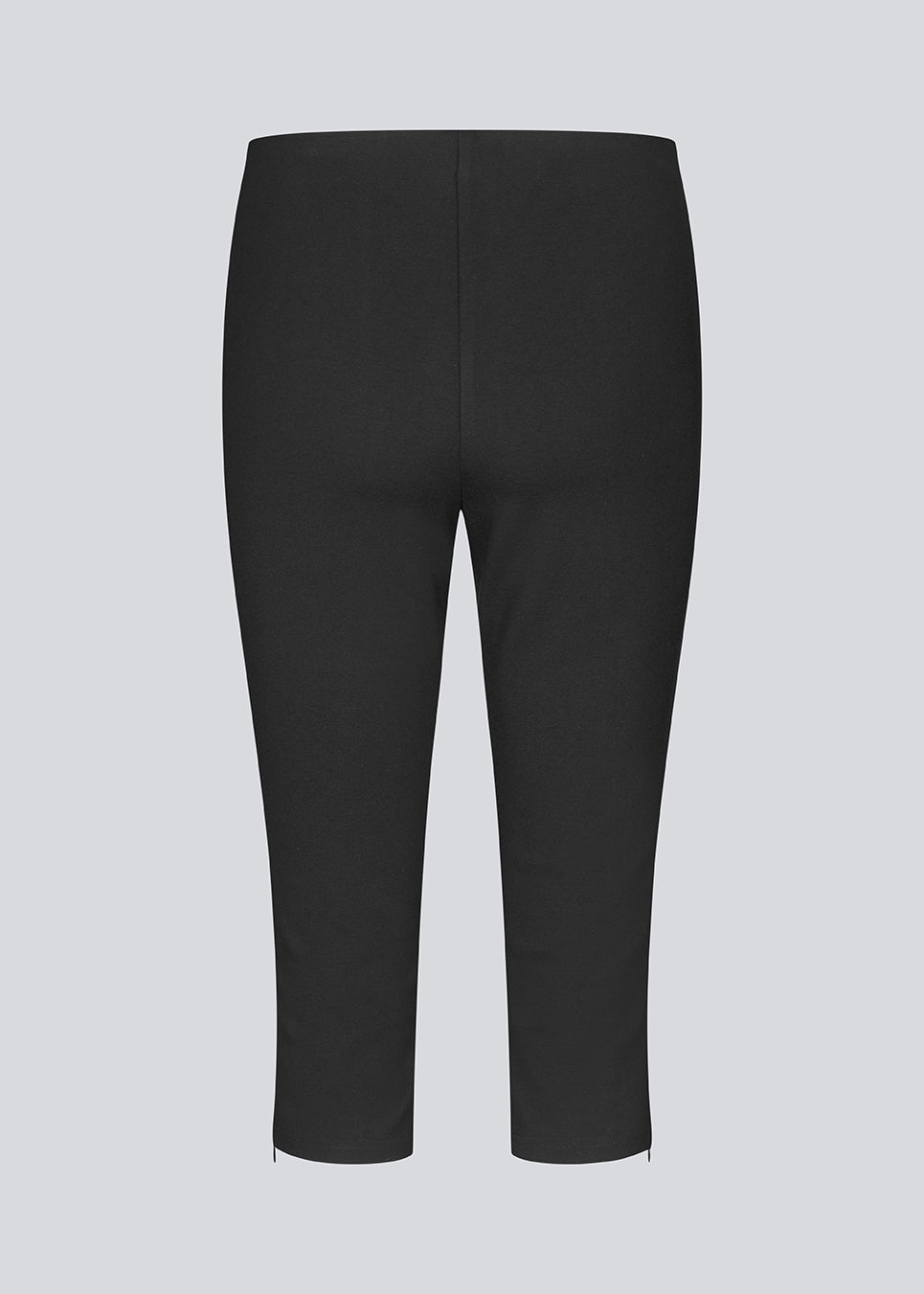 Black capri pants in a soft jersey material. Tanny capri pants has an elastic waistband and a slit with a zipper. The model is 175 cm and wears a size S/36.
