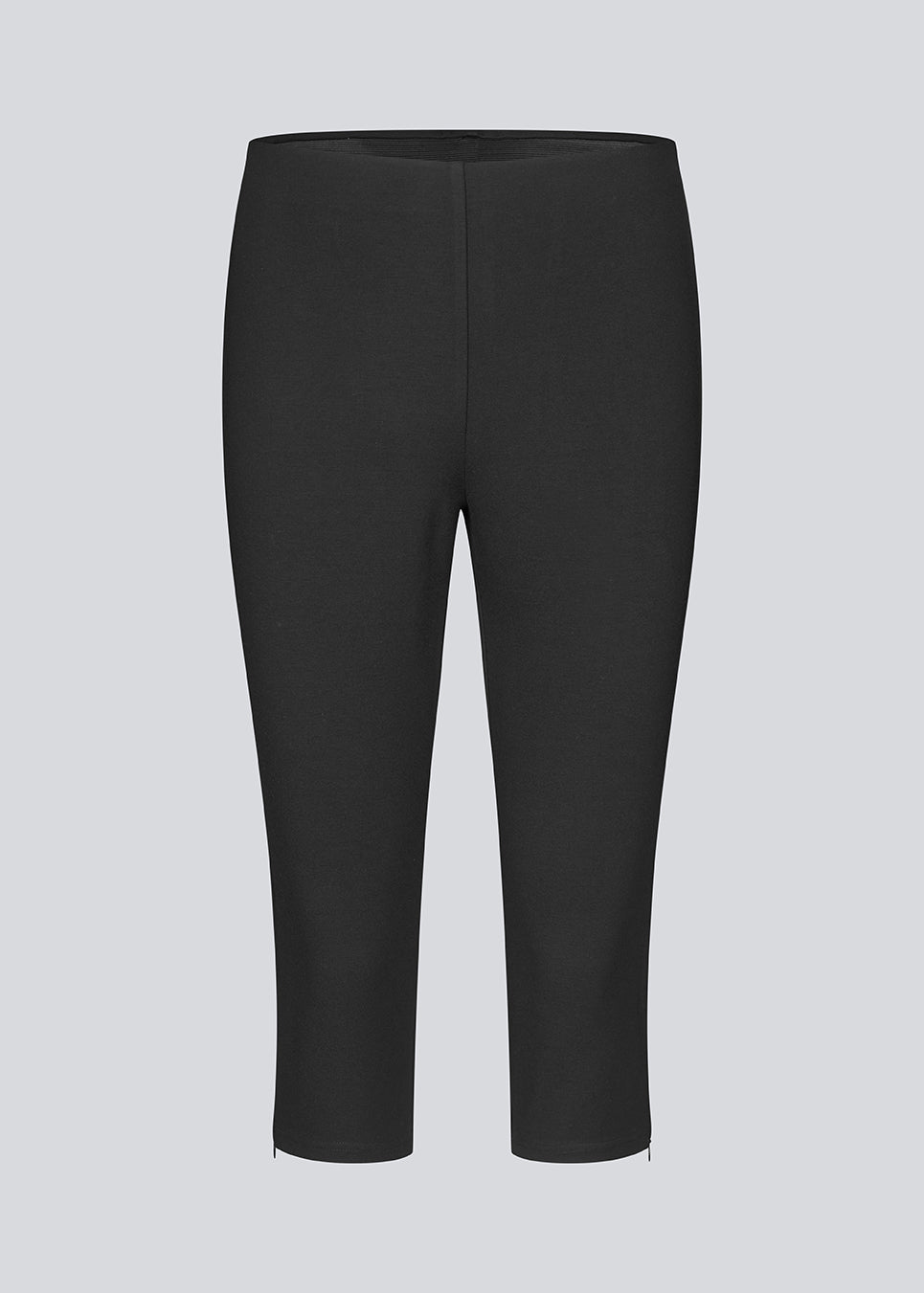 Black capri pants in a soft jersey material. Tanny capri pants has an elastic waistband and a slit with a zipper. The model is 175 cm and wears a size S/36.