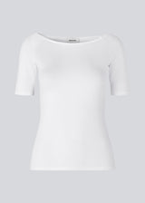 Tansy top in white has a simple look with a wide neckline at front and back and narrow sleeves. The top is slim fit without being tight.