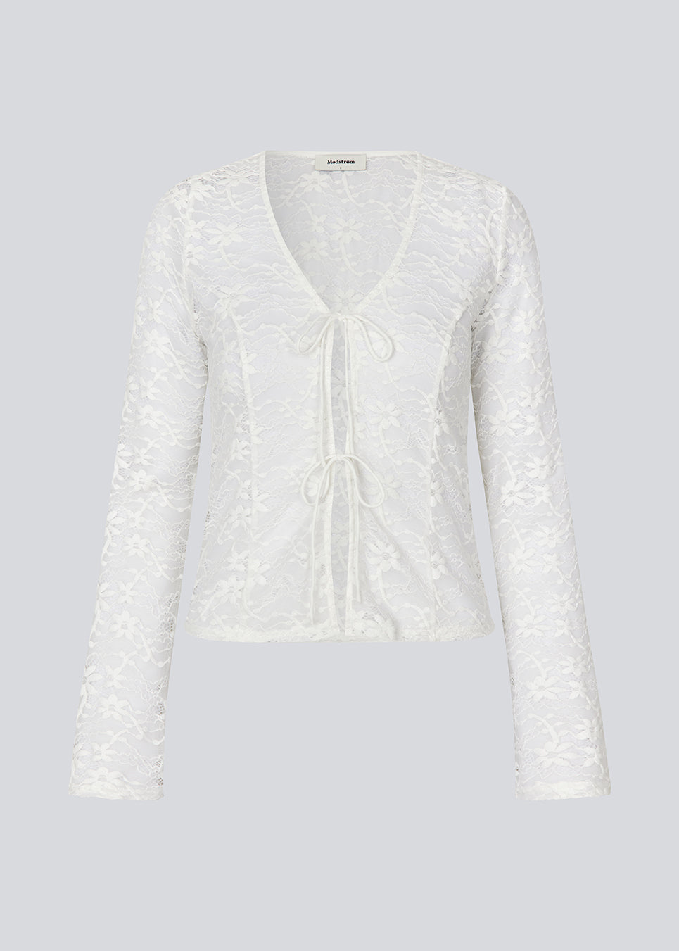 Fitted top in white stretchy lace with flared sleeves. TildeMD lace top has a deep V-neckline and two tiebands in the front.