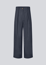 Suit pants in Twill with wide legs and pleats at the top in dark blue. ToreMD pants have a medium-high waist, zipper, side pockets and paspoil pocket in the back.