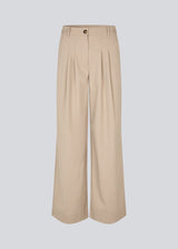 Suit pants in beige with pleats and wide leg. Tuesdaymd pants have a medium-highwaist, zipper, side pockets and paspoil pockets in the back. The model is 175 cm and wears a size s/36.