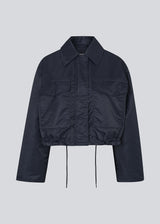Short jacket in navy with modern and practical details. The Ulrikkemd jacket features a classic collar, large front flap pockets, an adjustable drawstring at the waist, and is crafted from glossy nylon that gives it a sleek and sporty look. The model is 175 cm and wears a size S/36.
Material:
100% Nylon
Lining:
100% Polyester
Filling:
100% Polyester
