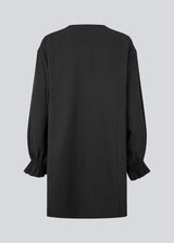 Elegant black dress in a lightweight textured fabric. The UrsaMD Dress features a relaxed, straight fit with long, voluminous sleeves and feminine ruffle details at the wrists. The round neckline has a small V-cut with tie strings, adding a delicate and relaxed touch.
Material:
40% Cotton
60% Recycled Polyester