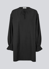 Elegant black dress in a lightweight textured fabric. The UrsaMD Dress features a relaxed, straight fit with long, voluminous sleeves and feminine ruffle details at the wrists. The round neckline has a small V-cut with tie strings, adding a delicate and relaxed touch.
Material:
40% Cotton
60% Recycled Polyester