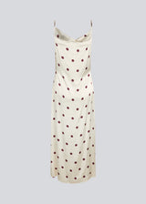 Long white satin dress with polka dots. The Vanjamd Print Dress features delicate spaghetti straps, a cowl neckline, and a loose, elegant drape that creates a feminine and modern look.