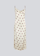 Long white satin dress with polka dots. The Vanjamd Print Dress features delicate spaghetti straps, a cowl neckline, and a loose, elegant drape that creates a feminine and modern look.