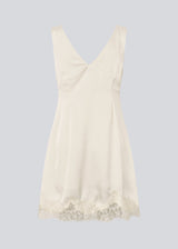Short satin dress in white/cream with lace details. Vuemd dress features wide straps, a crossed detail at the bust, and a hidden side zip. Elegant and feminine – ideal for both everyday wear and special occasions.