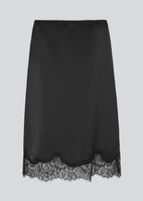 Black satin skirt with lace hem on a light gray background