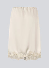 Elegant satin skirt in white/cream with lace details. VueMD skirt is a knee-length satin style with an elastic waist and a relaxed fit. Perfect worn alone or layered for versatile styling. 