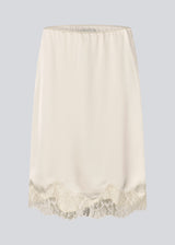 Elegant satin skirt in white/cream with lace details. VueMD skirt is a knee-length satin style with an elastic waist and a relaxed fit. Perfect worn alone or layered for versatile styling. 