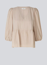 Top in beige in a loose silhouette with 3/4 length sleeves, v-shaped neckline and a cutline at the waist for ekstra volume on the bottom of the top.