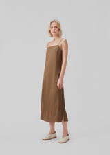 Slip in dress in satin with an A-shape and classic expression. CarwynMD dress has adjustable spaghetti straps and a straight neckline in front and back. The model is 177 cm and wears a size S/36.