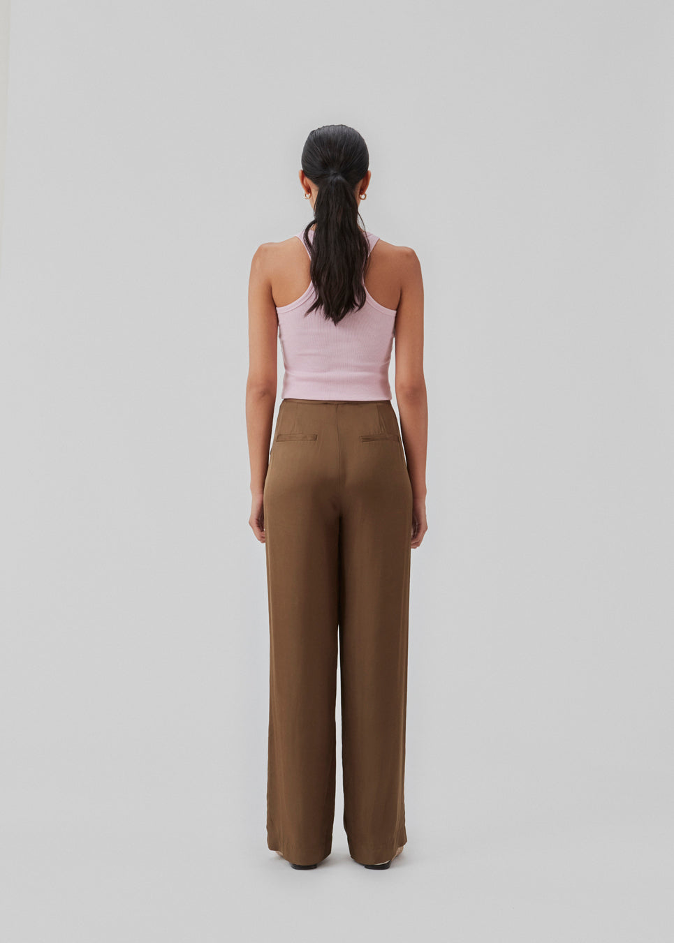 Satin pants in a classic look. CarwynMD pants are designed with wide legs, pleats in front, and hidden closure with zip fly and clasp. The model is 174 cm and wears a size S/36.