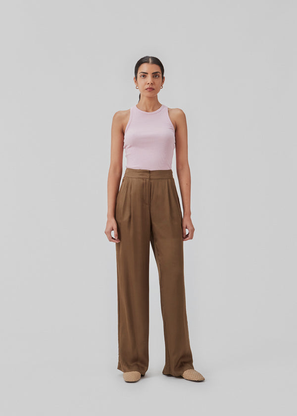 Satin pants in a classic look. CarwynMD pants are designed with wide legs, pleats in front, and hidden closure with zip fly and clasp. The model is 174 cm and wears a size S/36.