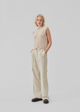 Crochet top in beige without sleeves in organic cotton. CaryMD top has detailed trimmings and a deep v-neckline in the back. The model is 177 cm and wears a size S/36.