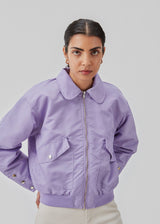 Short, padded bomber jacket in purple. ColtonMD jacket is designed with a collar, zipper in front, and pockets with push buttons. Ribbing at the hem.
