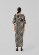 Long dress with a wide skirt and voluminous puff sleeves. CoraMD print dress has a round neck with a cut out and bow in the back. Made from organic cotton.  The model is 174 cm and wears a size S/36.