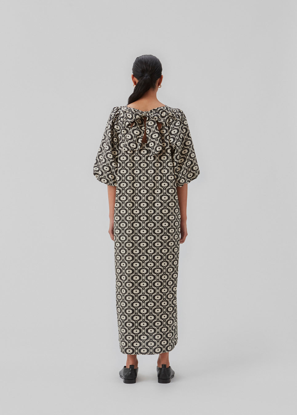Long dress with a wide skirt and voluminous puff sleeves. CoraMD print dress has a round neck with a cut out and bow in the back. Made from organic cotton.  The model is 174 cm and wears a size S/36.