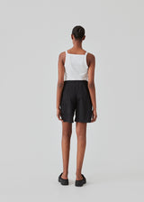 Tight fit basic white top with a high and straight neckline. DaeMD top is made from a rib-knitted organic cotton. The model is 177 cm and wears a size S/36.
