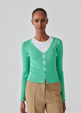 Slim fitted, slightly cropped cardigan in green with buttons at the front. DorisMD cardigan has a deep and round neckline, long sleeves, and lettuce hems. The model is 177 cm and wears a size S/36.