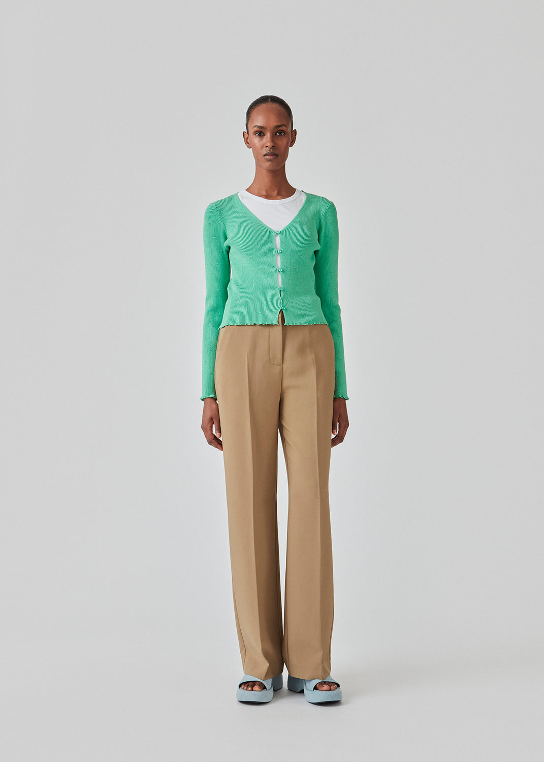 Slim fitted, slightly cropped cardigan in green with buttons at the front. DorisMD cardigan has a deep and round neckline, long sleeves, and lettuce hems. The model is 177 cm and wears a size S/36.