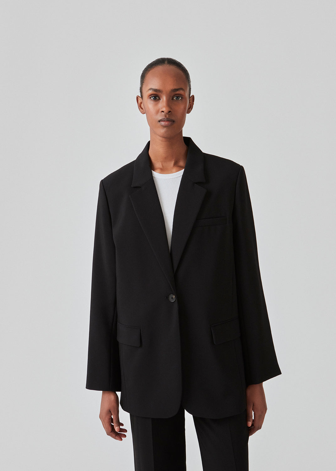 Gale blazer in Black has a classic and elegant design, fulfilled by the beautiful revers collar and a long fit. The blazer has a button closure at the front and a chest pocket at the left side. Buy Gale Pants, Gale straight pants, GaleMD skirt or GaleMD shorts in the same color that fits the Blazer.  The model is 177 cm and wears a size S/36.  This blazer has a spacious fit. We recommend sizing down.